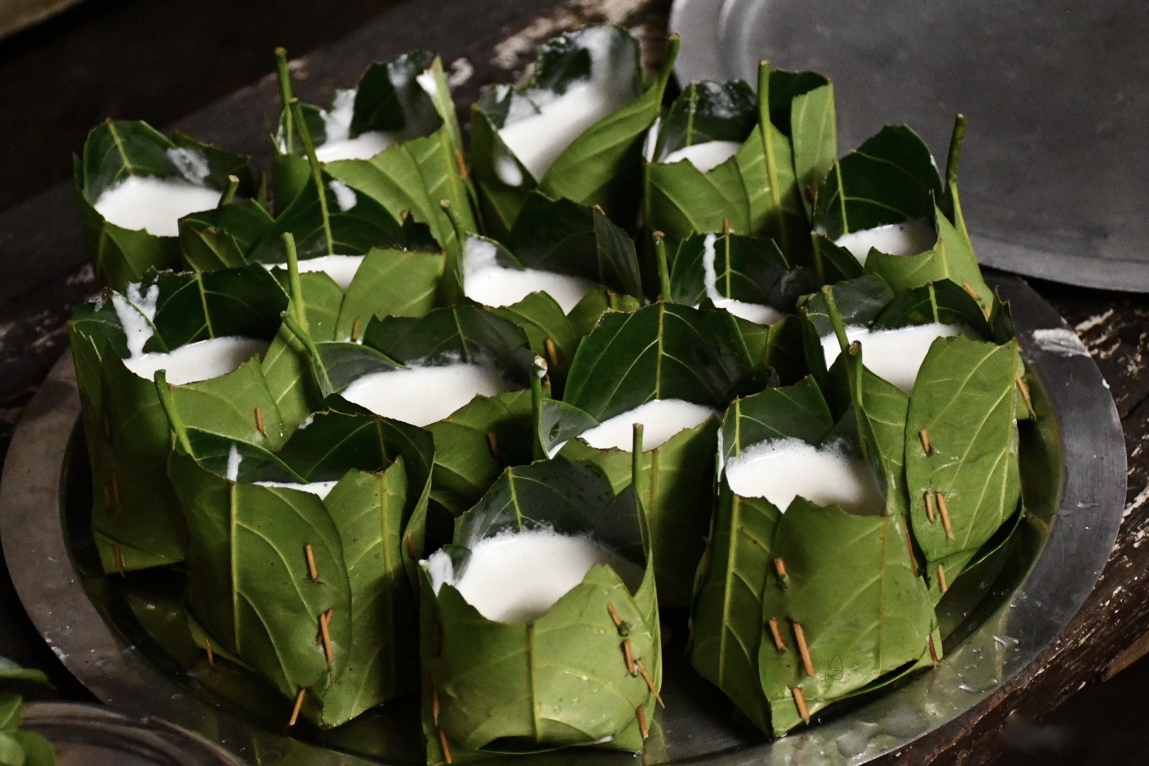 a tray of idli kotte in individual leaves.