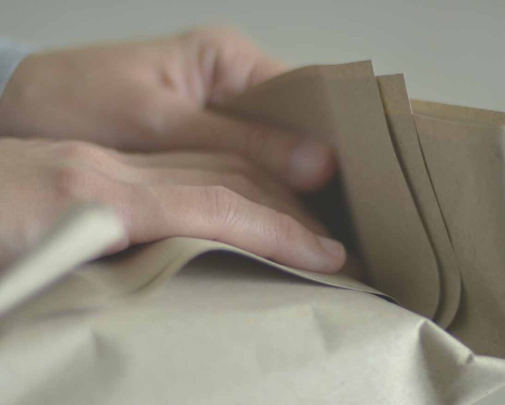 A picture of hands folding two tapow papers together.