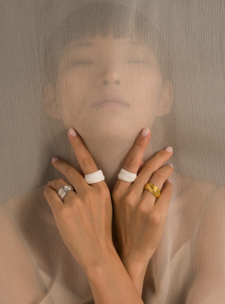 Photo of woman wearing four rings of porcelain and silver.