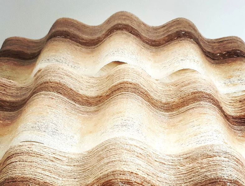 Photo of the 3D printed wood material which is printed in waves with different colours and textures.