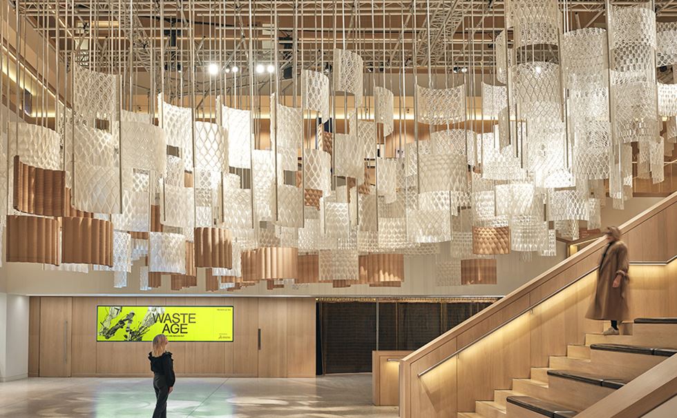Photo of the Aurora installation in the Design Museum atrium with hanging reflective modules, thin steel rods and wooden modules.