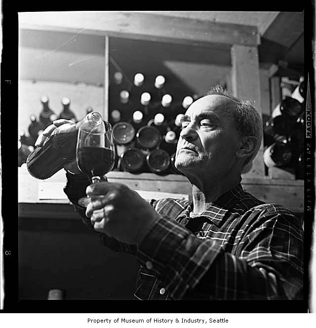A man pouring wine into a long-stemmed glass in a wine cellar.