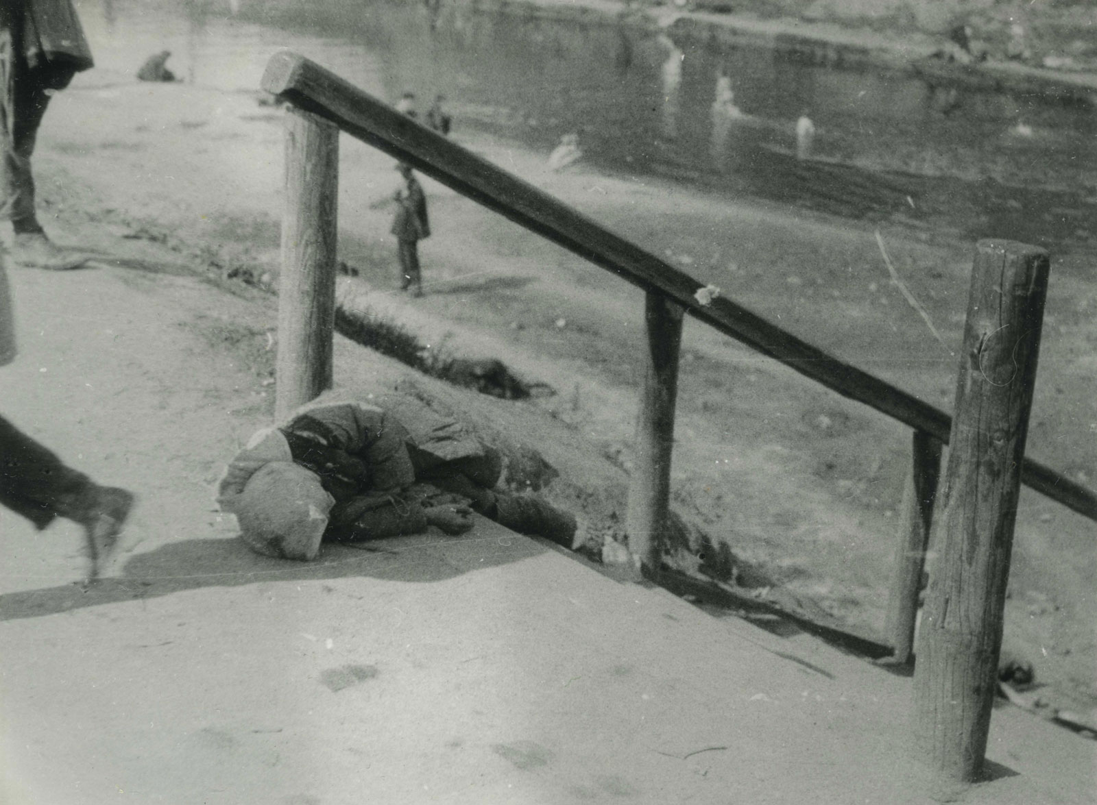 A black and white photograph of a girl's body lying alongside a flight of stairs outside.