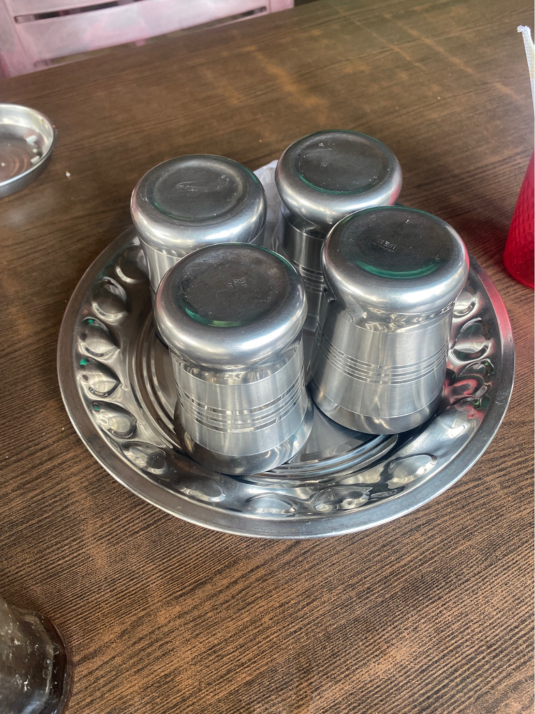 Four silver food containers rest on a dimpled silver plate