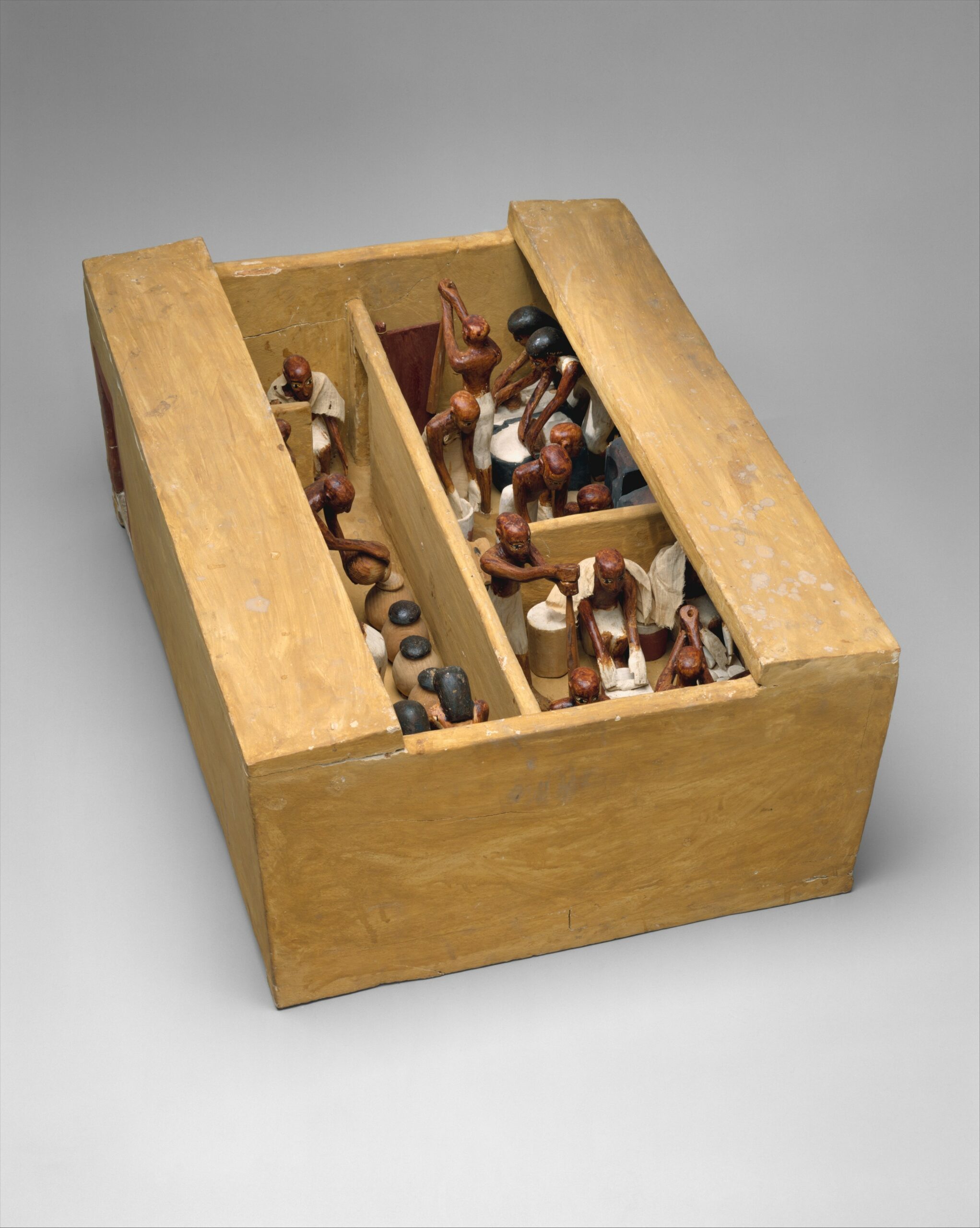 A miniature box divided into three portions each with scale models of small bakers working to bake food.