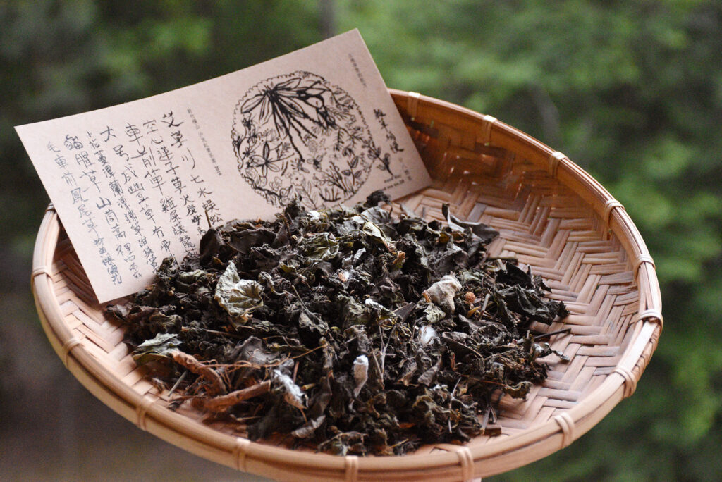A shallow woven basket holds dried herbal tea leaves as well as a card detailing ingredients.