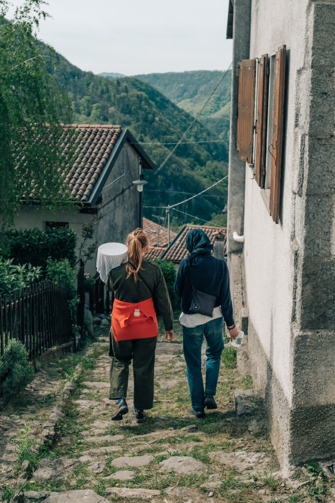 Two people walking down a narrow village street.