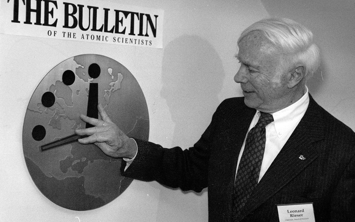 Leonard Rieser pointing to 'The Doomsday Clock', a graphic appearing like an anolog wall clock.