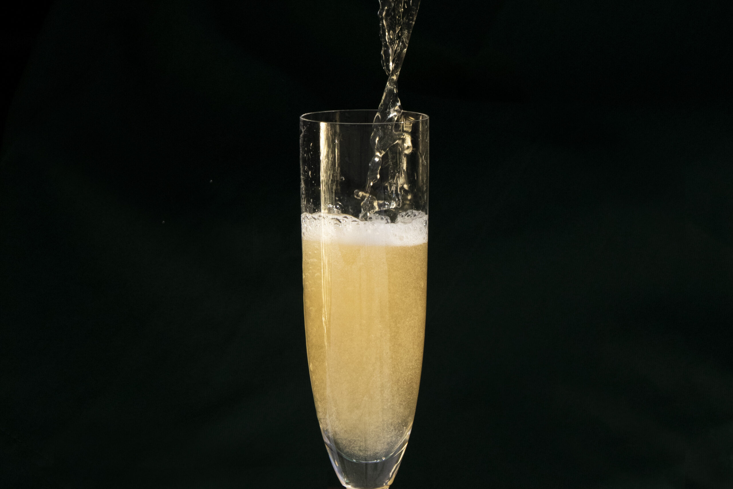 A champagne flute being filled with frothing yellow-ish palm wine.
