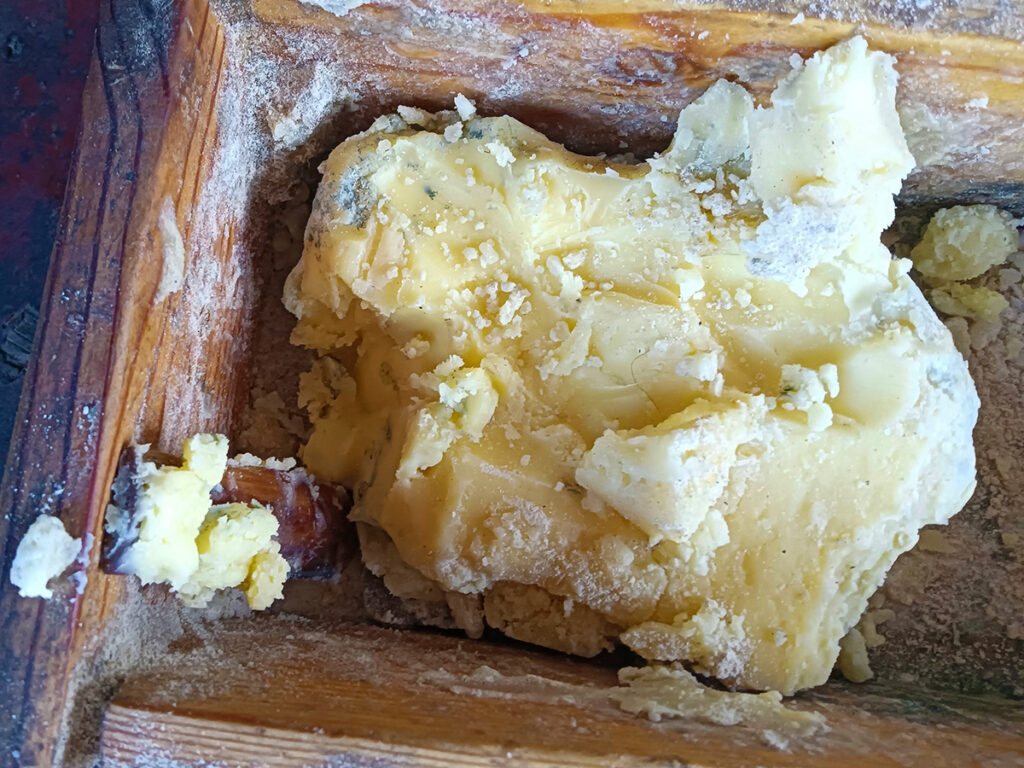 A wooden box holding a white-yellow ball of butter.