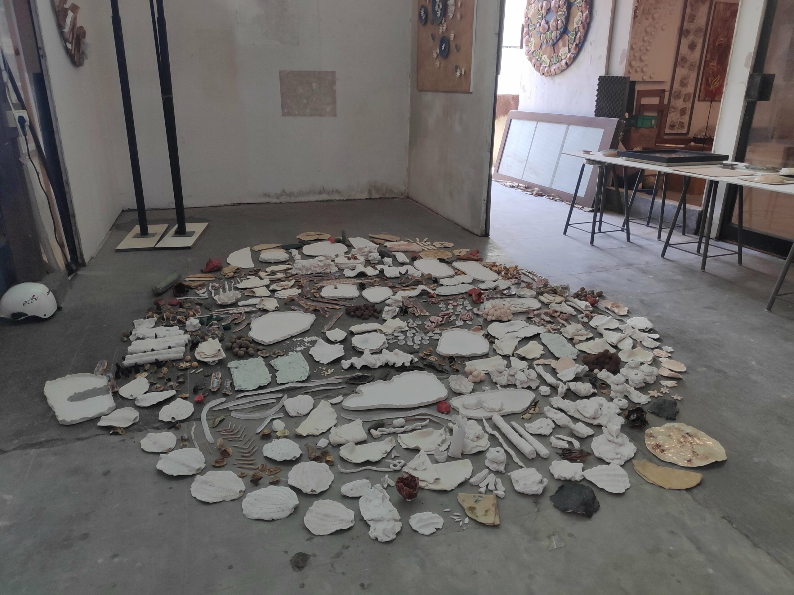 An assortment of over 50 ceramic pieces laid out on an artist studio floor.